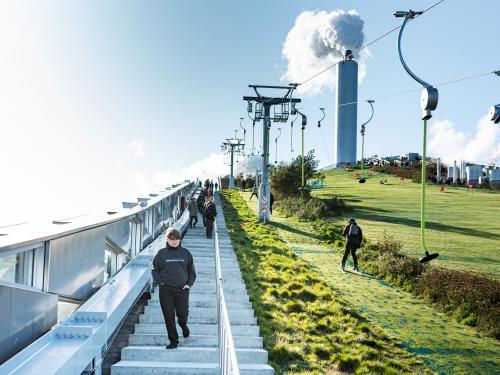 People skiing on a pitched green roof and stairs up to the roof